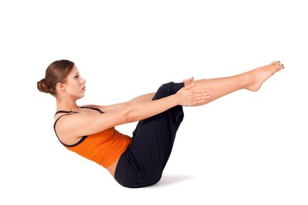 Woman doing first stage of yoga exercise called: Boat Pose, sanskrit name: Navasana, isolated on white backgroundの写真素材