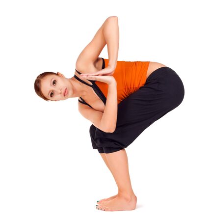 Young fit woman practicing yoga exercise called: Twisted Chair Pose sanskrit name: Parivrtta Utkatasana, isolated on white backgroundの写真素材
