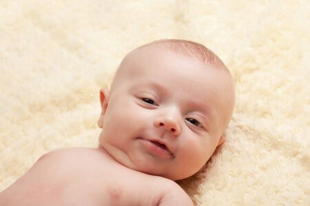 Six weeks old little baby girl lying on furry blanket looking at camera close-up on head and shouldersの写真素材