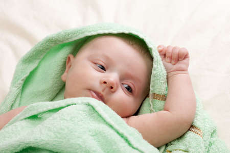 Beautiful six weeks old little baby girl wrapped in towel looking to the right の写真素材