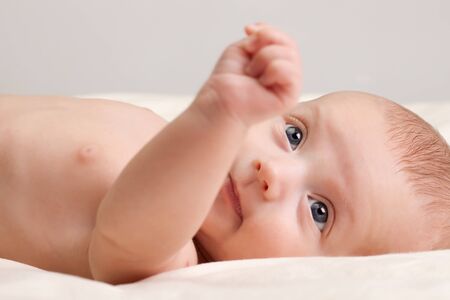 Ten weeks old cute little baby girl toddler with curious look on her face lying comfortably on bed