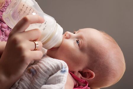Little baby girl drinking milk from bottleの写真素材