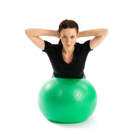 Pretty woman with hands behind head doing a pilates exercise using gym ball, isolated over a white backgroundの写真素材