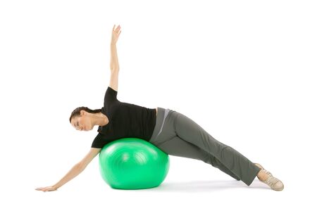 Pretty fit woman training with a pilates ball, isolated over a white backgroundの写真素材
