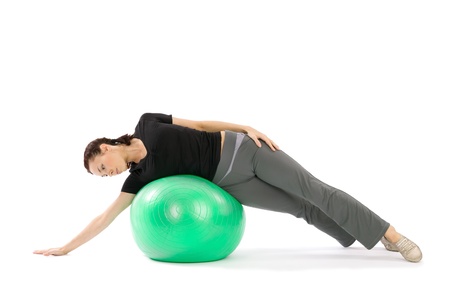 Pretty young fit woman practice with a pilates ball, isolated over a white backgroundの写真素材