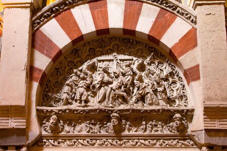 Religious carving framed by the Moorish Arabic arch, depicts the removal of Jesus Christ from the cross in Mezquita Cathedral, Andalusia, Spain の写真素材