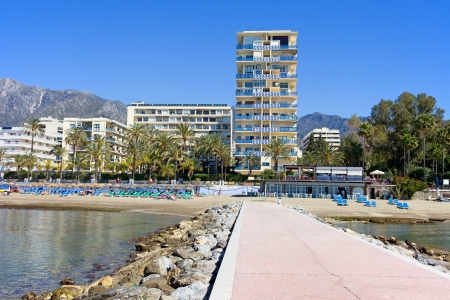Pier, beach and apartment buildings in resort town of Marbella on Costa del Sol in Spain, Andalusia, Malaga province.の写真素材