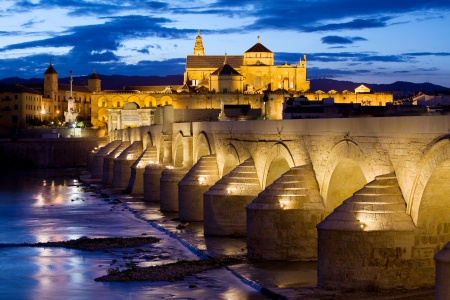 Roman Bridge on Guadalquivir river and Mosque Cathedral (La Mezquita) illuminated at dusk in the city of Cordoba, Andalusia, Spain.の写真素材