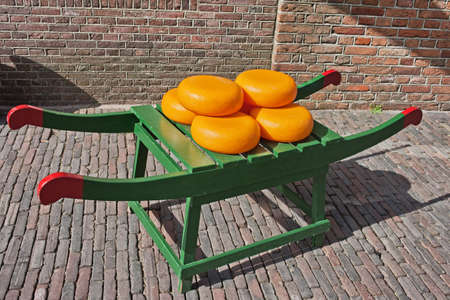 Wheels of Dutch Gouda cheese on traditional wooden barrow in Amsterdam, Netherlands, North Holland.