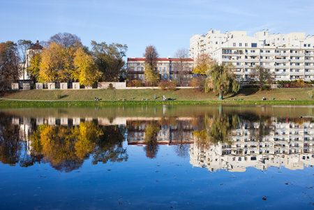 Skaryszewski Park in Warsaw, Poland. Apartment buildings and autumn trees by the lake with reflection on water.のeditorial素材