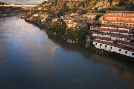 Sunset at Vila Nova de Gaia and Porto in Portugal. Wine cellars and warehouses on a steep shore of...