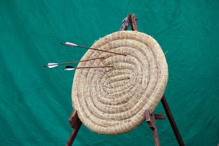 Traditional archery round coiled straw target on a stand with three arrowsの写真素材