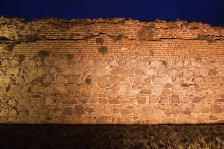 Teutonic Knights castle wall background illuminated at night in Torun, Poland, stone and brick medieval fortification.のeditorial素材