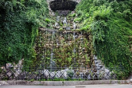 Hungary, Budapest, man-made waterfall on Gellert Hill, water cascade surrounded by lush creeping plantsの写真素材