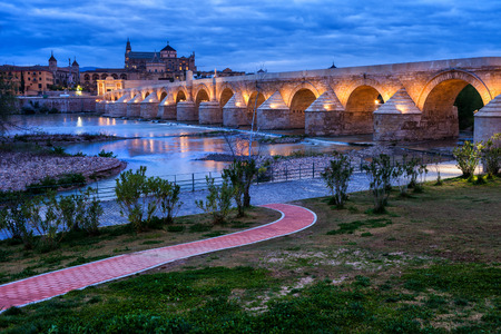 Spain, Cordoba, Roman Bridge (Puente Romano) on Guadalquivir River and Mosque Cathedral at twilightの写真素材