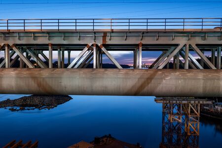 At Citadel Railway Bridge (Most przy Cytadeli) on Vistula River with large pipe on side at dusk in...