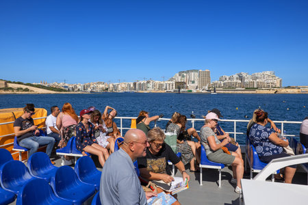 Valletta, Malta - October 17, 2019: Valleta Ferry Services boat with group of people, tourists on the top deck with Sliema skyline at Marsamxett Harbour, public transportのeditorial素材