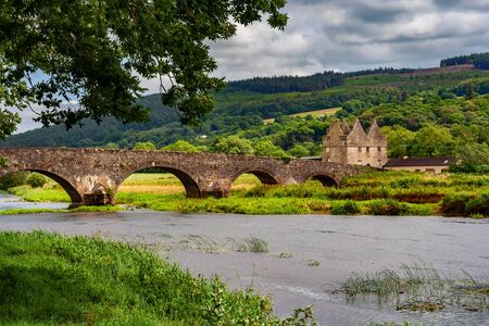 Old arched stone bridge over River Suir and County Tipperary landscape in Ireland