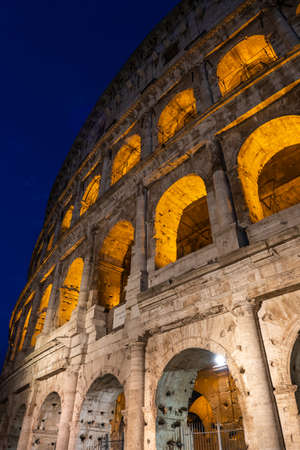 The Colosseum by night in Rome, Italy. Ancient Flavian Amphitheatre and Gladiators arena, famous city landmark.の写真素材