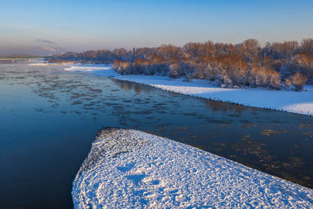 Winter landscape with Vistula river (Wisla) in Warsaw, Poland, snowy island, broken ice in water and...