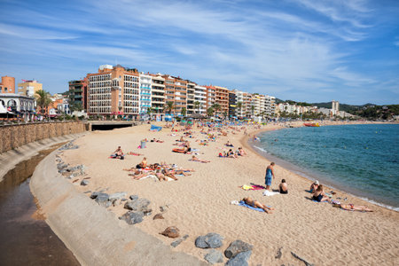 Lloret de Mar, Catalonia, Spain - October 5, 2016 - People relax on sandy beach in resort town on...