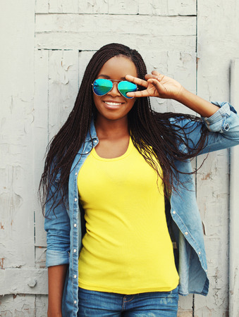 Portrait pretty smiling african woman in colorful clothes and sunglasses having funの写真素材