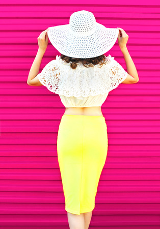 Fashion pretty woman in summer straw hat and skirt over colorful pinkの写真素材