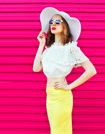 Fashion woman in summer straw hat and skirt over colorful pink backgroundの写真素材