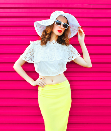 Woman in white summer straw hat and skirt over colorful pink backgroundの写真素材