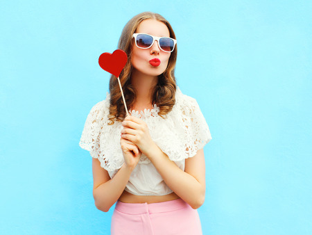 Portrait pretty woman and red lollipop over colorful blue backgroundの写真素材
