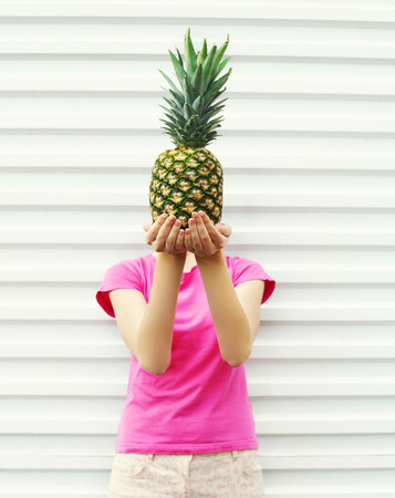 Woman and pineapple on her head standing over white backgroundの写真素材