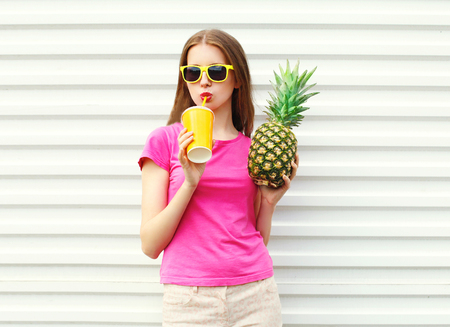 Fashion pretty cool girl drinking from cup with pineapple over white backgroundの写真素材