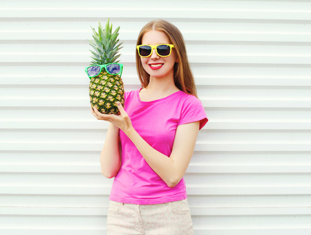 Fashion pretty girl in sunglasses with pineapple over white backgroundの写真素材