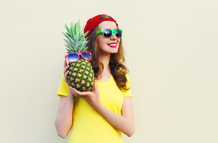 Fashion pretty happy smiling girl with pineapple over white backgroundの写真素材