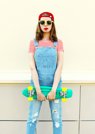 Fashion portrait pretty cool girl with skateboard over white backgroundの写真素材