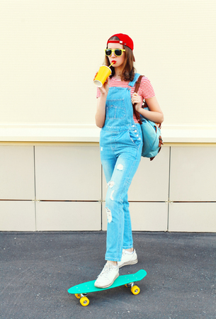 Fashion pretty cool girl with cup on skateboard over white backgroundの写真素材