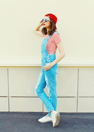Fashion pretty woman model in denim jumpsuit standing over white backgroundの写真素材