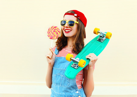portrait cool smiling girl with lollipop and skateboard over white backgroundの写真素材