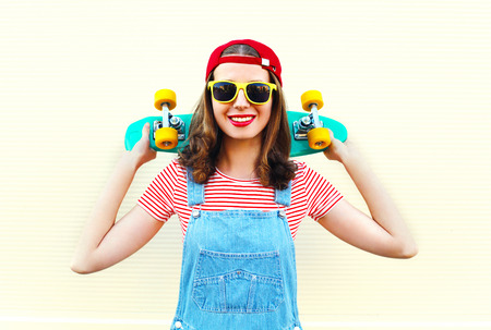 Pretty cool smiling woman with skateboard over white backgroundの写真素材
