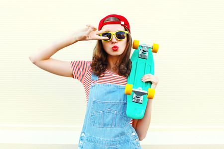 Pretty cool woman with skateboard having fun over white backgroundの写真素材