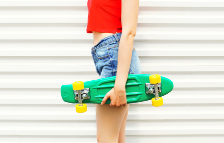 Fashion girl holding skateboard in denim shorts over white backgroundの写真素材