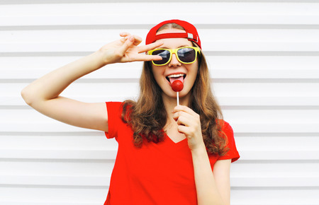 Fashion portrait cool girl with lollipop having fun over white backgroundの写真素材