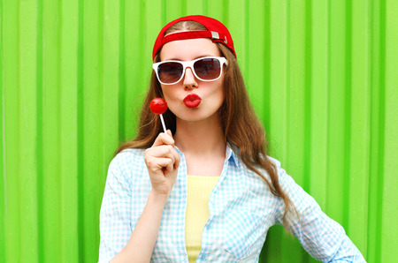 Fashion portrait pretty cool girl with lollipop over green backgroundの写真素材