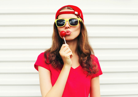Fashion portrait pretty cool girl with lollipop over white backgroundの写真素材