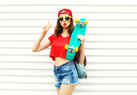Fashion pretty cool woman with skateboard in sunglasses and shorts over white backgroundの写真素材