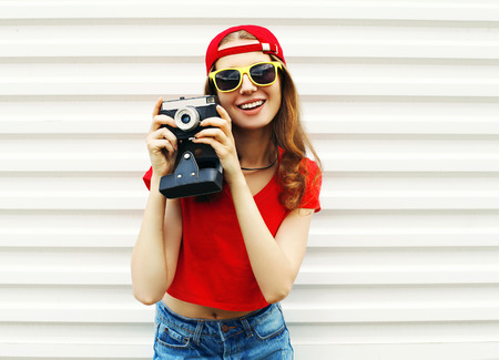 Fashion pretty smiling woman with retro camera having fun over white backgroundの写真素材