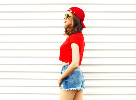 Fashion pretty woman in sunglasses and shorts looks away over white backgroundの写真素材