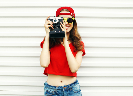 Fashion pretty smiling woman with retro camera over white backgroundの写真素材