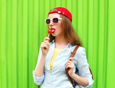 Portrait pretty cool girl with lollipop over green backgroundの写真素材