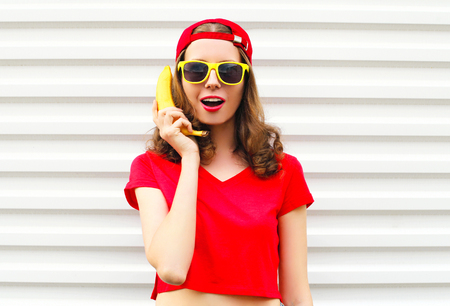 Portrait pretty cool woman with banana having fun over white backgroundの写真素材